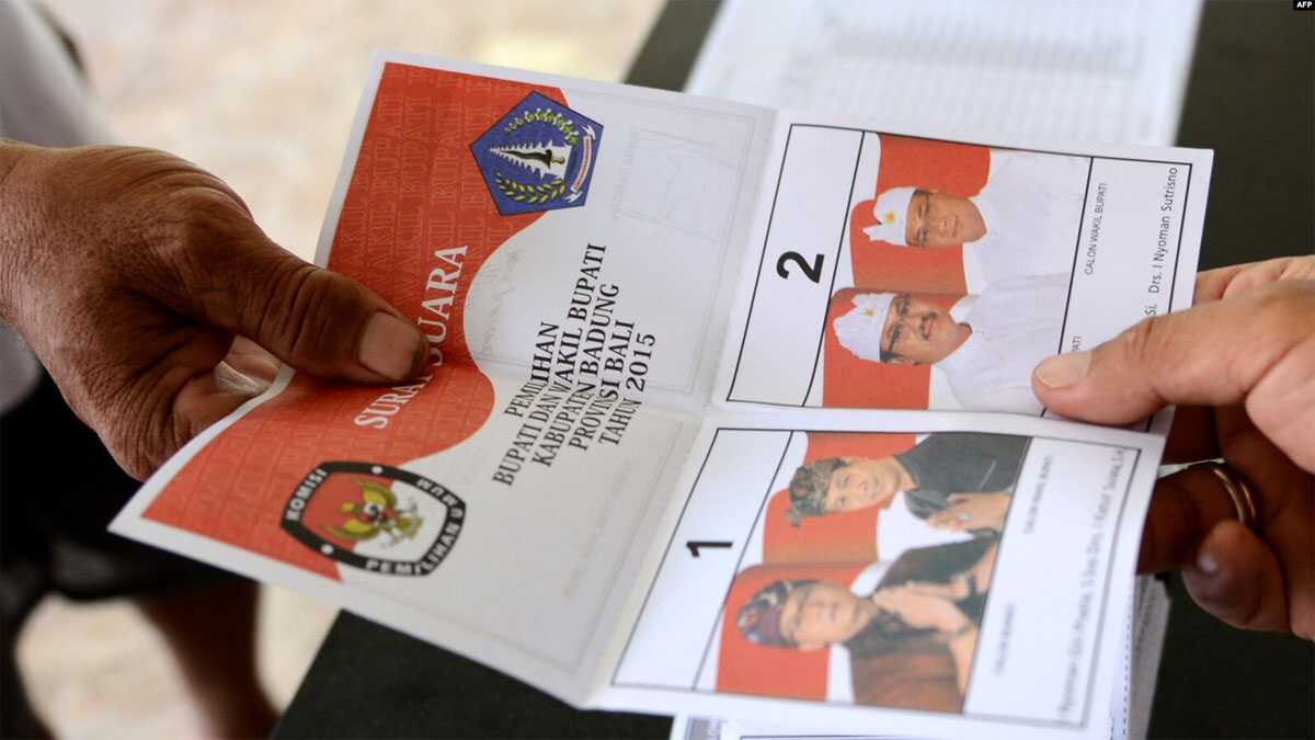 Pemilu 2015 Seorang petugas TPS memberikan surat suara di TPS di Kuta, Bali, saat pelaksanaan pilkada, 9 Desember 2015. (Foto: AFP)