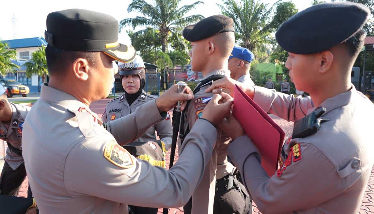 Kapolres Karimun AKBP Fadli Agus membuka pita tanda peserta latihan kerja dari salah seorang siswa SPN Polda Kepri dalam acara penutupan latihan kerja di lapangan apel Bhayangkara, Mapolres Karimun, Senin (11/12/2023). (Dok Humas Polres Karimun)