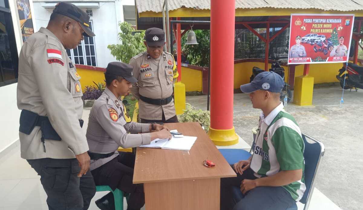 pos penitipan kendaraan Polsek Moro Kapolsek Moro AKP Rizal Rahim mengamati anggotanya yang mencatat data kendaraan bermotor warga yang akan dititipkan di tempat penitipan yang disiapkan Polsek Moro selama libur Natal dan Tahun Baru 2024, Sabtu (23/12/2023). (Dok Humas Polres Karimun)