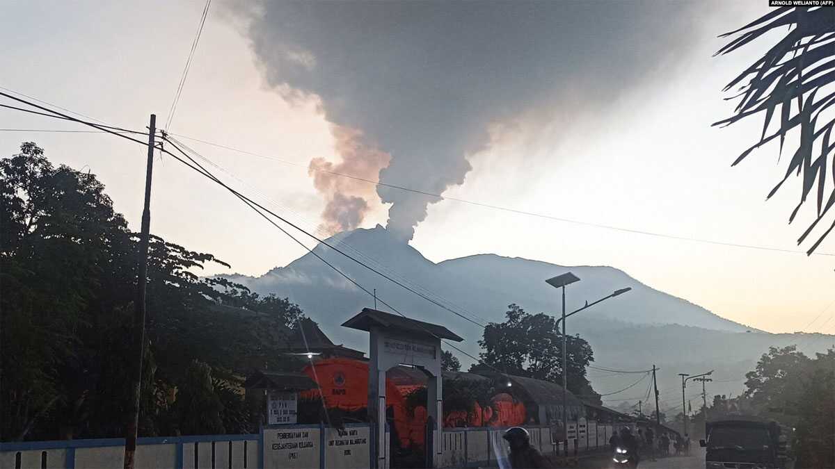 Pengendara berkendara saat Gunung Lewotobi Laki-Laki mengeluarkan asap panas di Flores Timur, Nusa Tenggara, Timur, 2 Januari 2024. (Foto: AFP/ARNOLD WELIANTO)