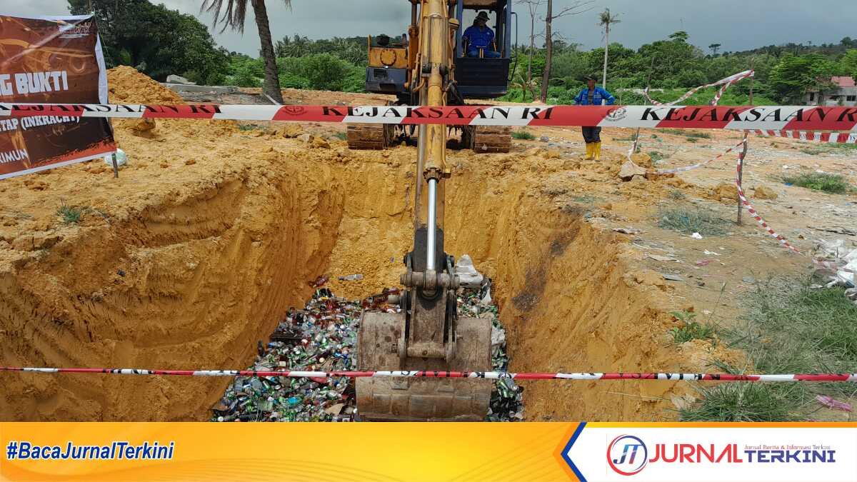 Alat berat menggilas ribuan botol minuman beralkohol berbagai merek sebelum ditimbun dengan tanah dalam kegiatan pemusnahan barang bukti oleh Kejari Karimun di TPA Sememal, Kelurahan Pasir Panjang, Kecamatan Meral Barat, Rabu (17/1/2024). (Jurnalterkini.id/yogi)