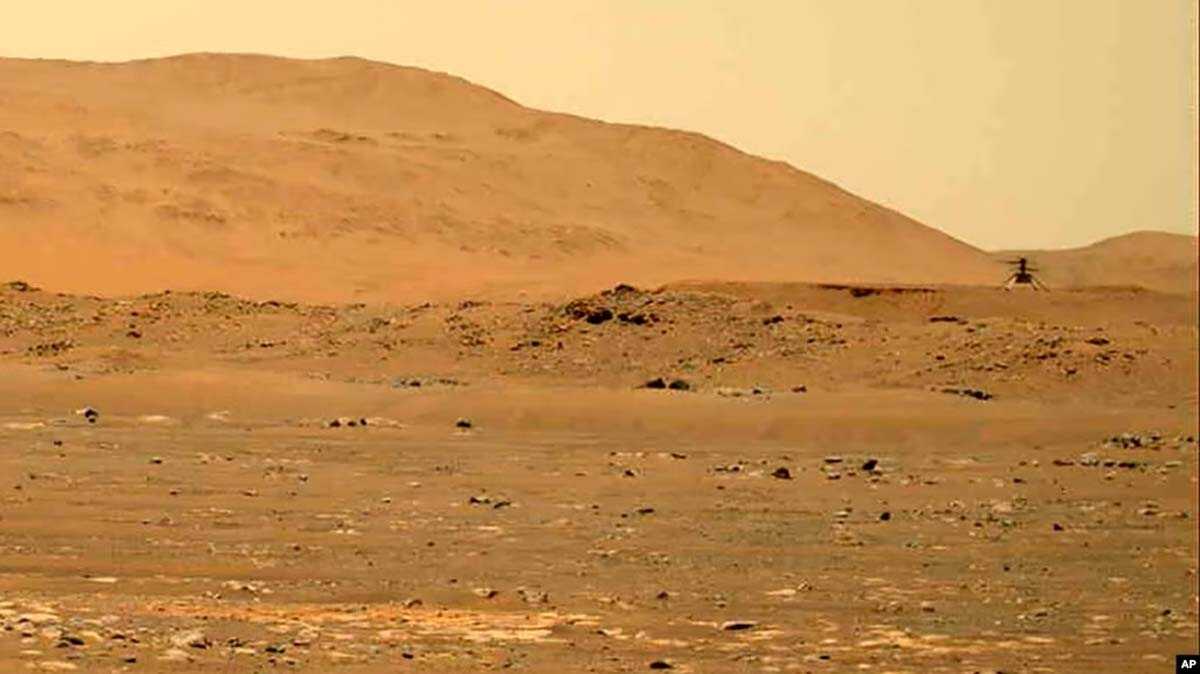 penjelajah mars persevarance Penjelajah Mars Perseverance menunjukkan helikopter Ingenuity, kanan, terbang di atas permukaan planet. (Foto: NASA via AP)
