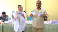 Bupati Karimun Aunur Rafiq beserta istri menunjukkan surat suara ketika menggunakan hak pilihnya dalam Pemilu 2024 di TPS 15 Kelurahan Sei Lakam Barat, Kecamatan Karimun, Rabu (14/2/2024). (Foto: Prokopim Karimun)
