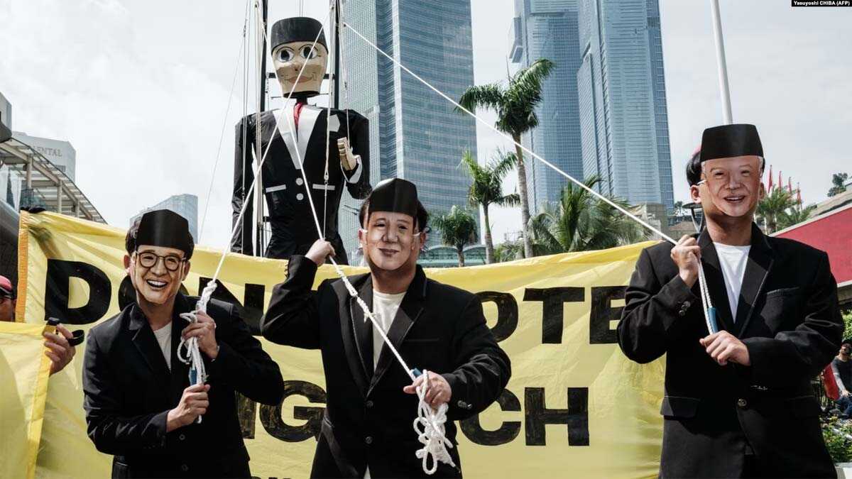 Peserta yang mengenakan masker wajah tiga calon presiden Anies Baswedan, Prabowo Subianto, dan Ganjar Pranowo berjalan di depan boneka raksasa bergambar Pinokio saat demonstrasi di Jakarta, 7 Februari 2024. (Foto : AFP/Yasuyoshi CHIBA)