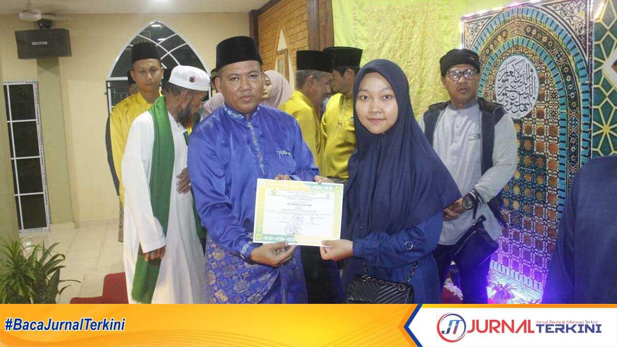 Camat Tebing Khaidir berpose dengan salah satu pemenang ajang Musabaqah Tilawatil Quran (MTQ) tingkat Kecamatan Tebing yang resmi ditutup pada Jumat (23/2/2024). (foto: jurnalterkini.id/edy)