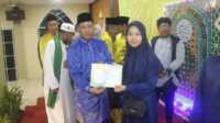 Camat Tebing Khaidir berpose dengan salah satu pemenang ajang Musabaqah Tilawatil Quran (MTQ) tingkat Kecamatan Tebing yang resmi ditutup pada Jumat (23/2/2024). (foto: jurnalterkini.id/edy)