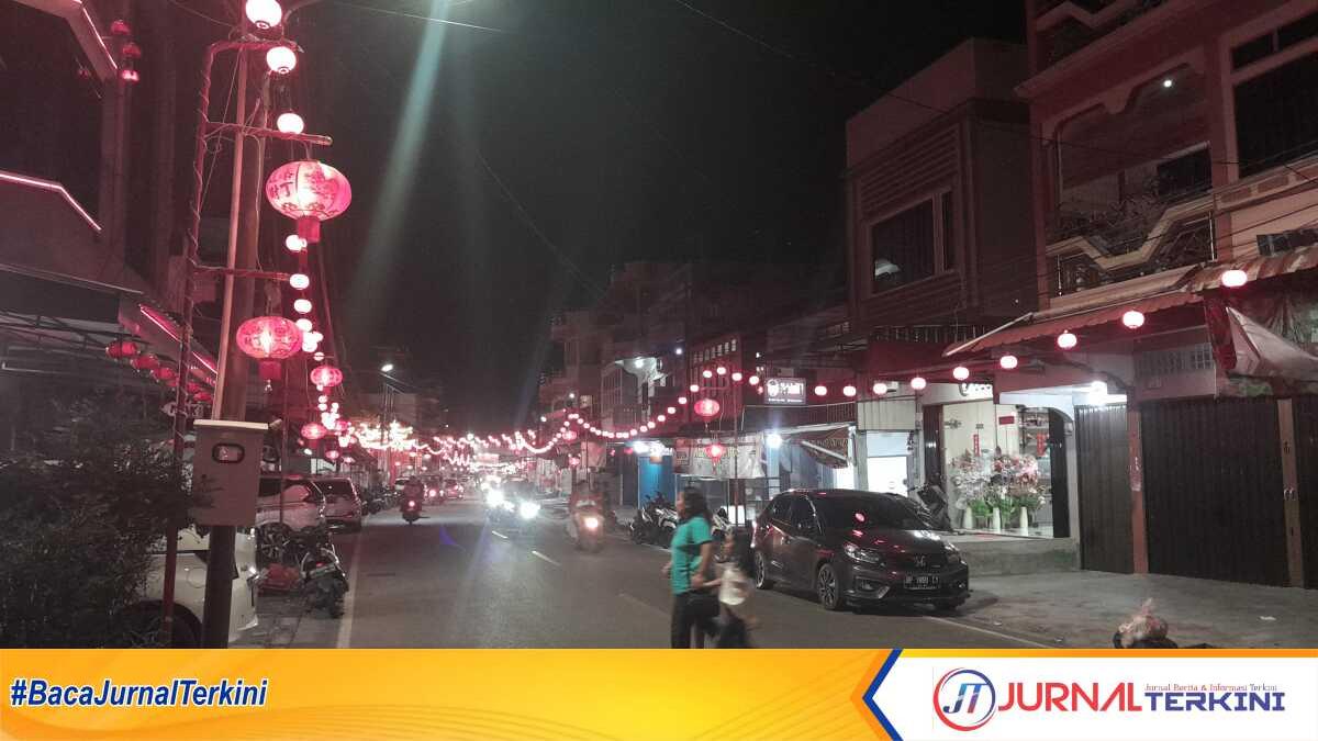 Warga menyeberangi jalan raya di Meral Kota, Kecamatan Meral Kabupaten Karimun yang memerah diterangi ribuan lampion, Minggu (4/2/2024). Penyalaan ribuan lampion di kawasan ini sudah menjadi tradisi dalam menyambut Tahun Baru Imlek, tidak terkecuali Tahun Baru Imlek 2575/2024 yang merupakan Tahun Naga Kayu. (jurnalterkini.id/jansen)