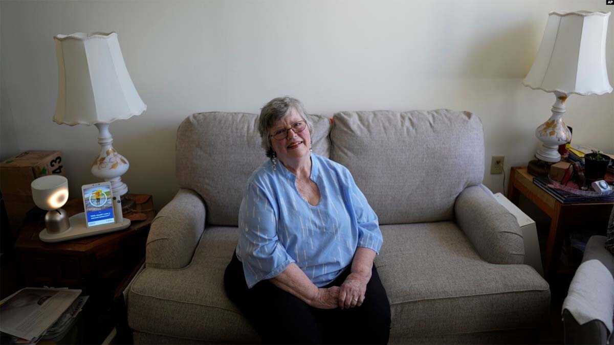 robot teman kesepian di masa tua Joyce Loazia berpose di sebelah robot ElliQ di apartemen khusus bagi komunitas lansia di Coral Springs, Florida. (Foto: AP/Rebecca Blackwell)