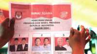 Seorang petugas pemilu memegang surat suara yang menunjukkan suara capres Prabowo Subianto dan pasangannya Gibran Rakabuming Raka, saat penghitungan suara di TPS setelah pemilu di Jakarta, Rabu, 14 Februari 2024. (AP/Tatan Syuflana)