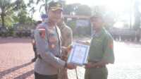 Kapolres Karimun AKBP Fadli Agus memberikan penghargaan kepada Supriadi, anggota Linmas yang bertugas membantu pengamanan Pemilu di TPS 11 Kelurahan Darussalam, Kecamatan Meral Barat. Penghargaan diberikan dalam upacara Hari Kesadaran Nasional di Mapolres Karimun, Selasa (19/2/2024). (jurnalterkini.id/jansen)