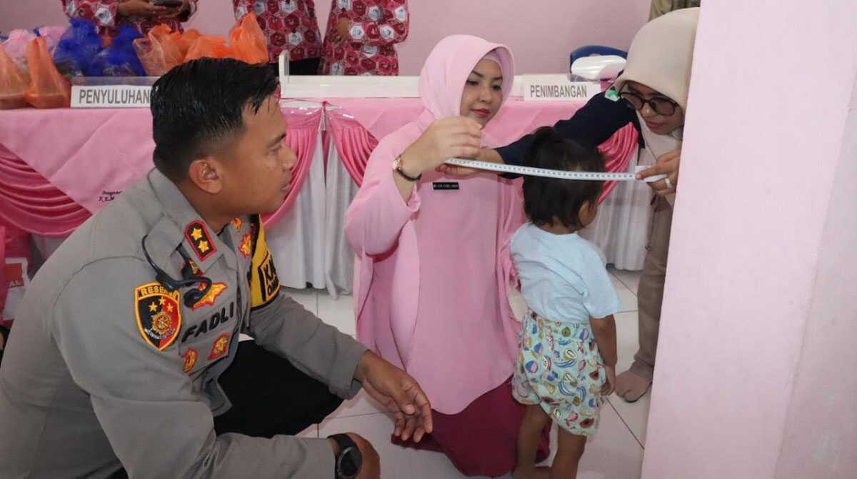 Ketua Bhayangkari Cabang Karimun Lya Fadli Agus didampingi Kapolres Karimun AKBP Fadli Agus mengukur lingkar kepala seorang balita di sela pemberian vitamin A untuk mencegah stunting di kalangan anak anggota polisi diselenggarakn di Posyandu Asrama Polisi, Kapling, Tanjung Balai Karimun, Selasa (27/2/2024). (jurnalterkini.id/jansen)