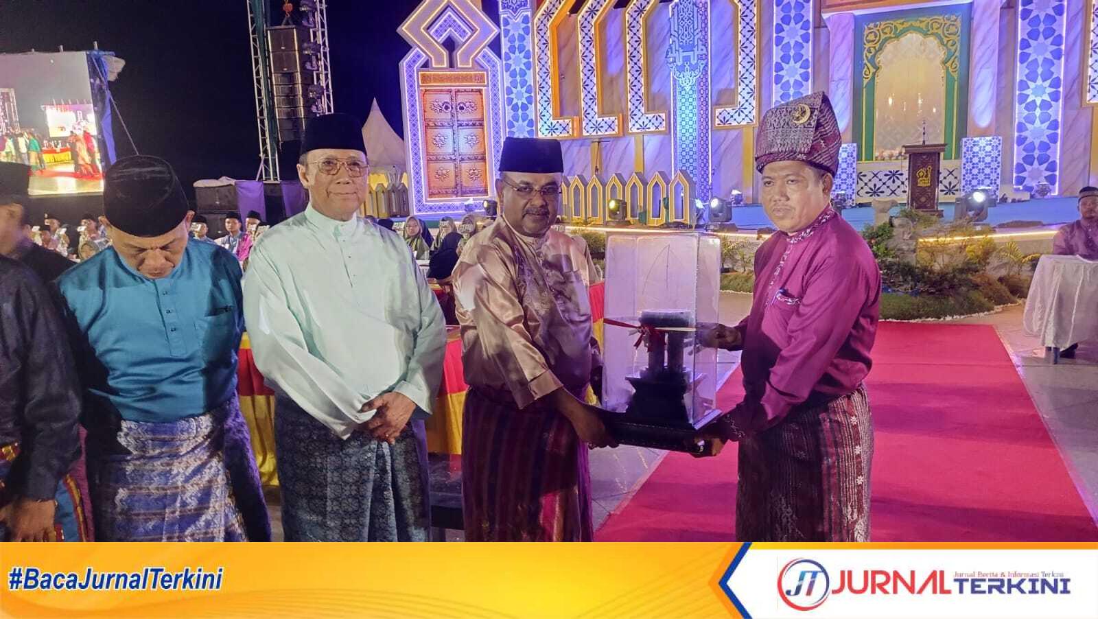 Bupati Karimun Aunur Rafiq menyerahkan tropi juara umum kepada Camat Tebing Khaidir Saleh dalam acara penutupan MTQ XVI tingkat Kabupaten Karimun di Coastal Area, Tanjung Balai Karimun, Minggu (21/4/2024) malam. (jurnalterkini.id/edy kencana)