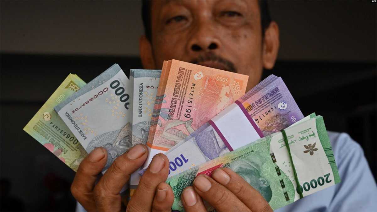 Seorang pria memperlihatkan uang kertas Rupiah baru yang akan diberikan kepada anggota keluarganya selama perayaan Idulfitri pada 28 Maret 2024. (Foto: AFP)