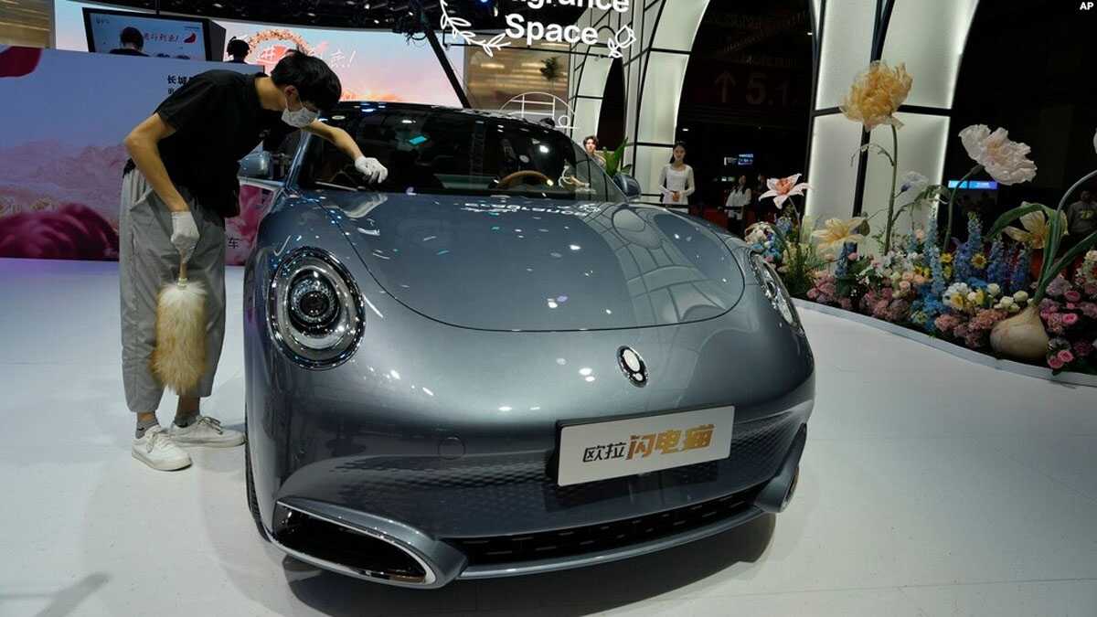 Seorang pekerja membersihkan Ora, sebuah mobil listrik Tiongkok, selama Auto Shanghai 2023 di sebuah pusat konvensi di Shanghai, 18 April 2023. (Foto: AP)