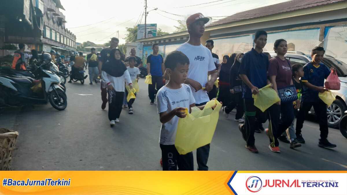 jalan santai sambil pungut sampah Peserta jalan santai Hari Bhayangkar ke-78 membawa kantong plastik tempat mengumpulkan sampah yang mereka temui selama berjalan di depan Pasar Puan Maimun, Tanjung Balai Karimun, Minggu (9/6/2024) pagi. (jurnalterkini.id/yogi)