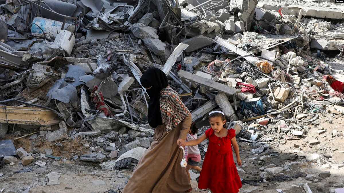 kamp nuseirat gaza Seorang perempuan dan anak-anak berjalan di antara reruntuhan bangunan di kamp pengungsi Nuseirat di Gaza tengah, pada 9 Juni 2024. Bangunan kamp hancur akibat serangan Israel ke area tersebut. (Foto: Reuters/Abed Khaled)