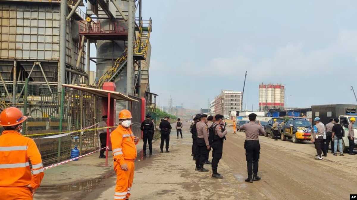 Petugas polisi dan pekerja berdiri di dekat lokasi ledakan tungku di pabrik peleburan Stainless Steel PT Indonesia Tsingshan di Morowali, Sulawesi Tengah, 24 Desember 2023. (Foto: AP)