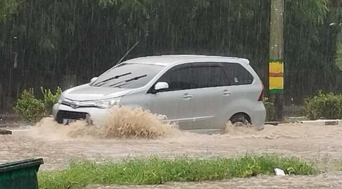 Sebuah mobil melintas di atas genangan air yang membanjiri ruas Jalan Jenderal Soedirman, Poros, tepatnya di depan Perumahan Bella Vista, Minggu (14/7/2024) sore. (dokumentasi pribadi/Ami)