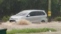 banjir di jalan poros Sebuah mobil melintas di atas genangan air yang membanjiri ruas Jalan Jenderal Soedirman, Poros, tepatnya di depan Perumahan Bella Vista, Minggu (14/7/2024) sore. (dokumentasi pribadi/Ami)