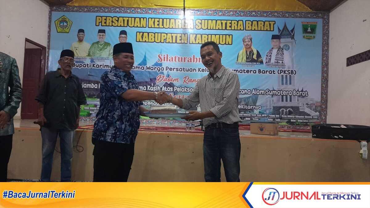Ketua PKSB Karimun Novi Hendri menyerahkan satu paket kue kepada Ketua Kerukunan Keluarga Daerah Pariaman (KKDP) Karimun, Hizbulwatan, selaku pemenang kedua lelang. (jurnalterkini.id/rusdi)