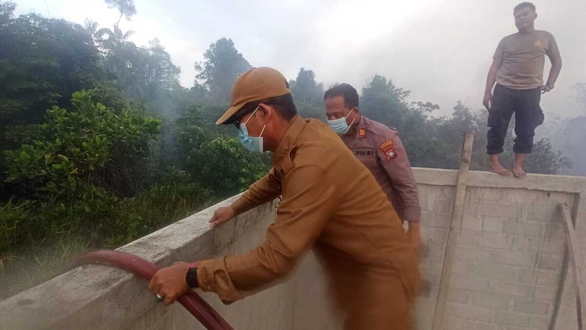 Kapolsek Kundur Barat AKP Effendi Marpaung bersama pegawai daerah setempat memadamkan api yang membakar lahan di Kelurahan Sawang pada Senin (22/7/2024). (foto: Polsek Kuba)