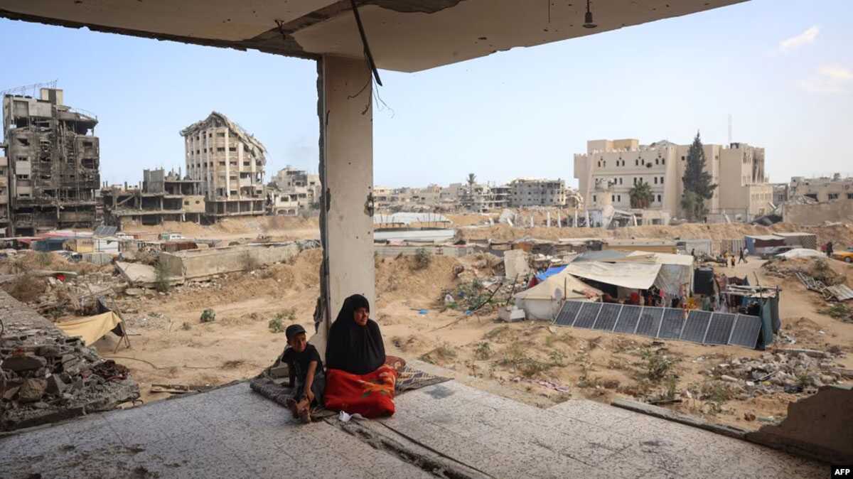 Satu keluarga Palestina duduk di sisa-sisa rumah mereka yang rusak akibat pengeboman Israel sebelumnya, ketika beberapa warga kembali ke kota Khan Yunis, di Jalur Gaza selatan pada 30 Juni 2024. (Foto: AFP)
