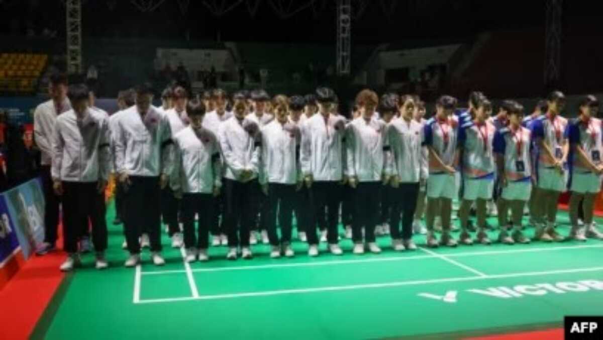 pebulutangkis Junior Tiongkok meninggal di lapangan Para pebulutangkis dan pelatih Tiongkok (mengenakan jaket putih dan ban lengan hitam) dan sejumlah pemain lainnya mengheningkan cipta mengenang wafatnya Zhang Zhijie, pebulutangkis junior Tiongkok, di turnamen Kejuara Asia Junior di Yogyakarta, pada 1 Juli 2024. (Foto: PBSI/AFP)