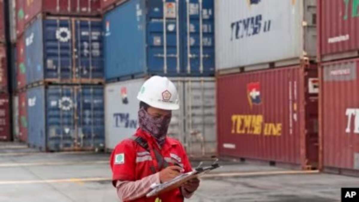 Seorang pekerja sedang mencatat data dekat tumpukan peti kemas di pelabuhan Tanjung Priok, Jakarta, 8 Oktober 2021. (Foto: Tatan Syuflana/AP Photo)
