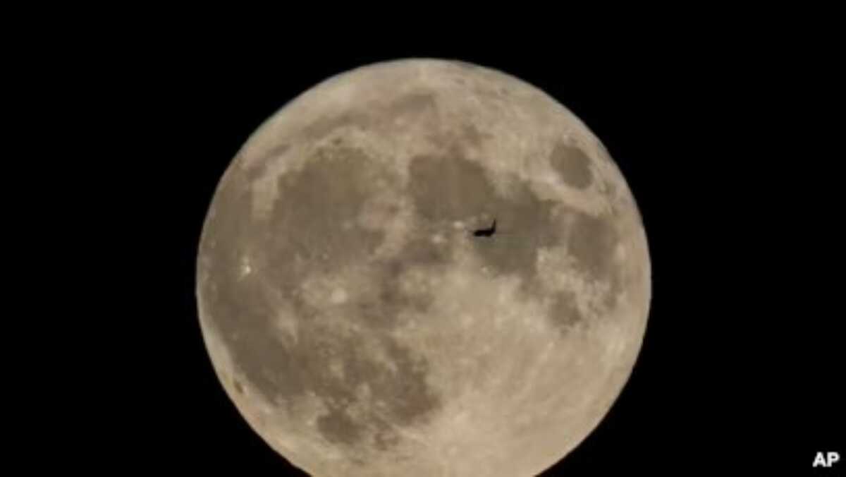 Sebuah pesawat terbang di depan bulan di Chicago, pada 30 Agustus 2023. (Foto: AP/Kiichiro Sato)