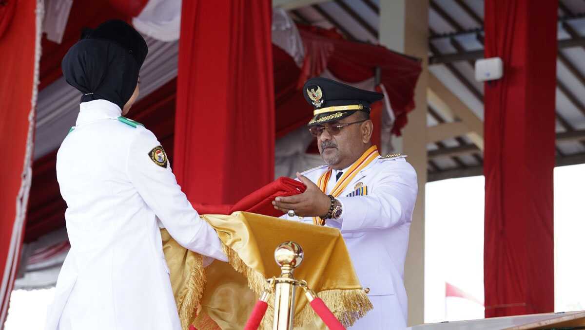 aunur rafiq terakhir pimpin upacara hut ri Bupati Karimun Aunur Rafiq menyerahkan bendera merah putih kepada pembawa, Ifta Laili Nur'ain saat menjadi inspektur upacara HUT RI ke-79 di Coastal Area, Tanjung Balai Karimun, Sabtu (17/8/2024). (foto: diskominfo karimun)