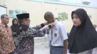 Kepala Badan Kesatuan Bangsa dan Politik (Kesbangpol) Indragiri Hilir H Arifin mengalungkan tanda peserta kepada salah satu calon Paskibraka yang mengikuti pemusatan pendidikan dan pelatihan di salah satu hotel di Tembilahan, Rabu (31/7/2924). (JurnalTerkini.id/Abdullah)
