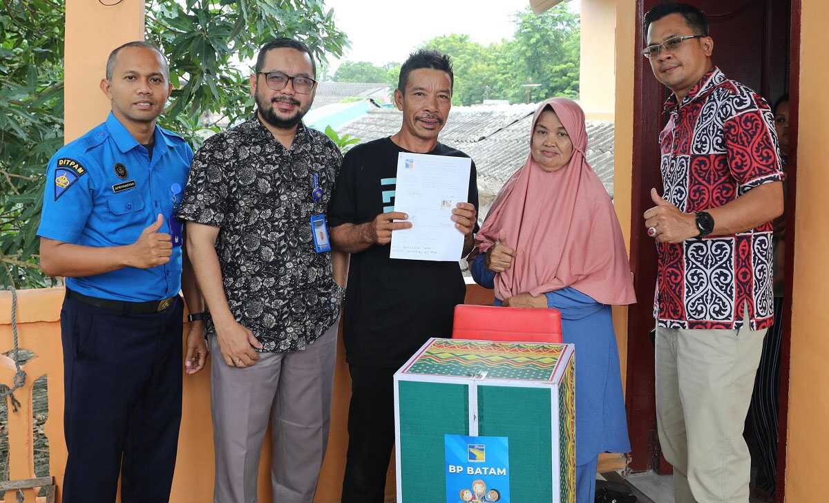 Ahmat Zulimin bersama istri, berpose dengan petugas BP Batam ketika bergeser ke hunian sementara, Rabu (7/8/2024). (foto: humas bp batam)