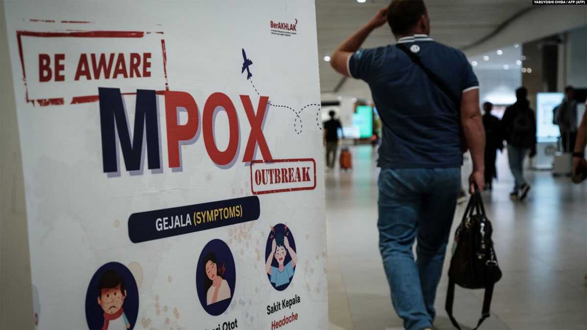 waspada cacar monyet Seorang penumpang berjalan melewati spanduk yang menginformasikan tentang Cacar Monyet (MPOX) di Bandara Internasional Soekarno-Hatta di Tangerang, 26 Agustus 2024. (YASUYOSHI CHIBA/AFP)