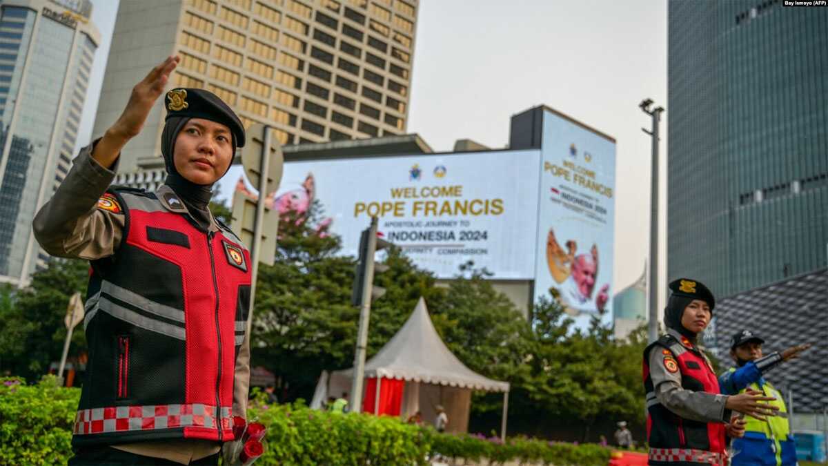polisi berjaga sambut paus fransiskus Polisi mengatur arus lalu lintas di dekat baliho bertuliskan selamat datang untuk Paus Fransiskus di Jakarta pada 2 September 2024. (Foto: AFP/Bay Ismoyo)