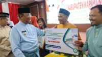 Plt Bupati Karimun Anwar Hasyim secara simbolis menyerahkan bantuan tempat sampah dari BPJS Kesehatan dalam acara syukuran HUT Kabupaten Karimun yang ke-25 di Gedung Nilam Sari, Kantor Bupati Karimun pada Sabtu (12/10/2024). (JurnalTerkini.id/edy kencana)