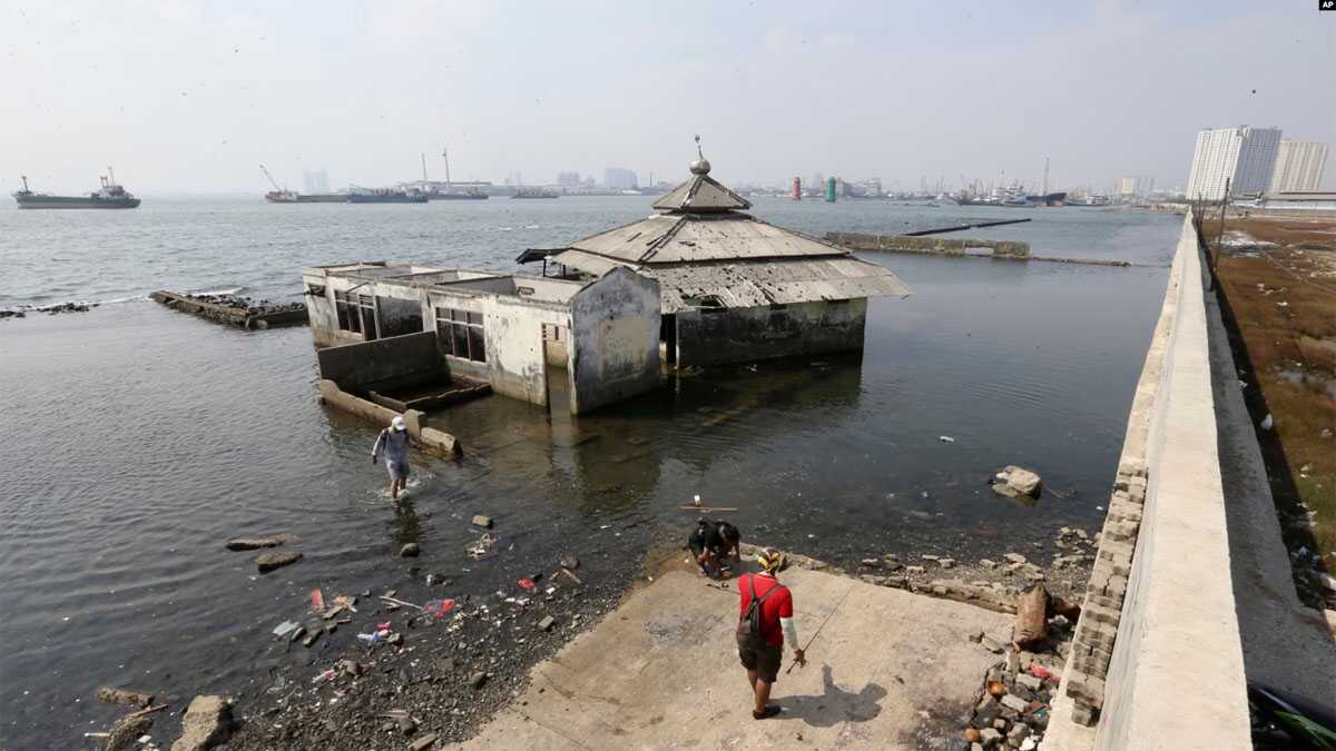 tanggul laut raksasa di jakarta Orang-orang berjalan di dekat tanggul laut raksasa yang digunakan sebagai pembatas untuk mencegah air laut mengalir ke daratan dan menyebabkan banjir di Jakarta, 27 Juli 2019. (Achmad Ibrahim/AP)