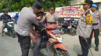 Kapolres Inhil AKBP Farouk Oktora saat memberikan helm Gratis kepada pengendara motor dalam rangka lanjutan Operasi Keselamatan Lancang Kuning 2025. (Humas polres Inhil)