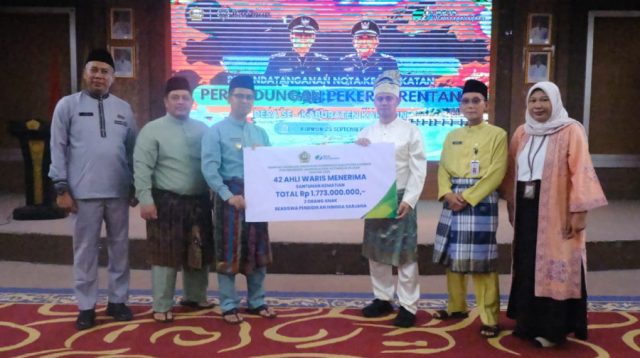 Bupati Karimun Iskandarsyah secara simbolis menyerahkan santunan kepada ahli waris peserta jaminan kematian di BPJS Ketenagakerjaan dalam acara di Gedung Nilam Sari, Kantor Bupati Karimun, Jumat (25/9/2026). (Foto: Diskominfostaper Karimun)